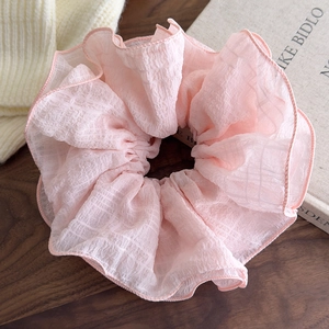 Macro shot of pink layered ruffle scrunchie on wood desk with cozy aesthetic vibes