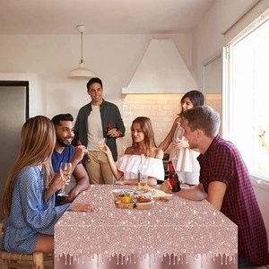 Group of people celebrating around a table with a rose gold sequin drip tablecloth