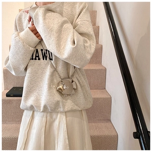 Close-up of a silver fish-shaped metallic chain bag worn by a model in a casual setting