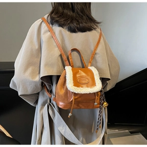 Close-up of brown faux leather and beige faux fur mini backpack with metal tassel detail