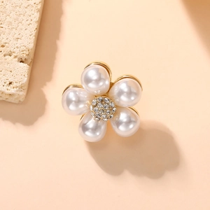 Detailed view of floral brooch with pearlescent petals and center zircon cluster