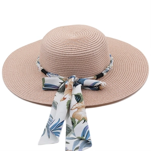 Detailed texture of straw sun hat with elegant pearl beads and tropical floral scarf bow