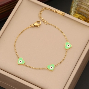 Detail of gold heart charms with green evil eye enamel on a stainless steel chain
