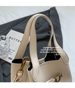 Close-up of white lychee pattern leather handbag with gold metal hooks and dual handles