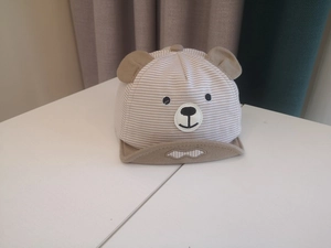 Detail of baby striped sun hat featuring cute bear ears and embroidered animal face
