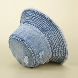 Detail of distressed denim bucket hat with frayed edges and vintage washed finish