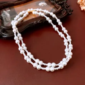 Double-layer glass pearl necklace with gold circular clasp on a vintage leather background