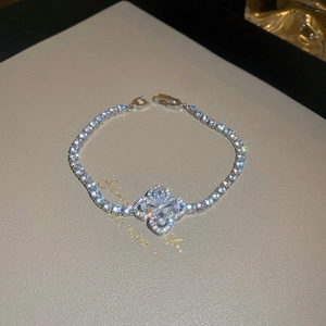 Macro shot of a silver clover bracelet with sparkling clear zircons on leather display