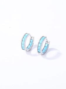 Detalle de pendientes de aro plateados con incrustación cuadrada azul cielo y relieve