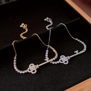 Detail of gold and silver key pendants with pave-set zircons on adjustable bolo bracelets