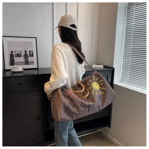 Detail view of large grey canvas travel bag with colorful doodle print and shoulder strap