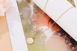 Détail d'un collier doré avec un pendentif rond orné de la lettre U majuscule gravée