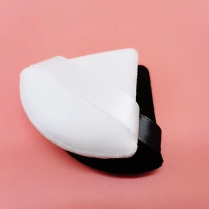 Detail of triangular velvet makeup puffs in black and white with satin ribbon handles