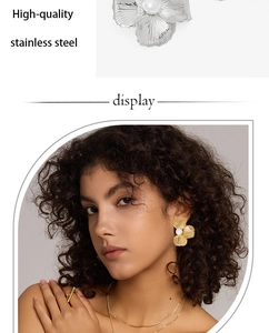 Detail of elegant stainless steel floral earrings with pearls in gold and silver finish