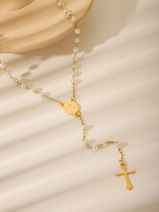 Detailed macro of a gold cross pendant and religious medal on a pearl rosary necklace