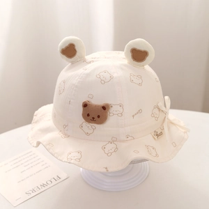 Close-up of cute bear ear baby sun hat in off-white cotton with drawstring and bow detail