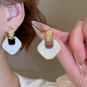 Detailed view of gold hammered U-shape earrings with white glossy finish on ear