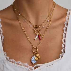 Detalle de collares en capas de acero inoxidable de 18K con perlas y colgantes de concha