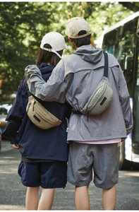 Outdoor street view of couple wearing khaki and green nylon crossbody bags on back