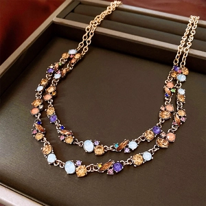 Macro view of double-layered gold chain necklace featuring colorful faceted crystals