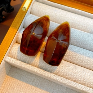 Macro detail of geometric amber resin earrings with faceted cuts in a wooden box