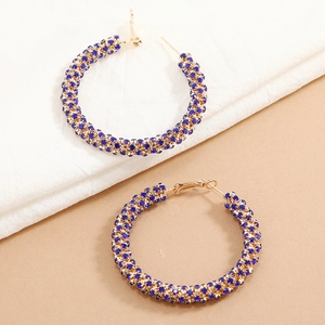 Detailed macro view of large gold hoop earrings with inlaid dark blue crystal diamonds