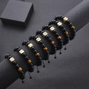 Detail of tiger eye bead bracelet with gold initial charms on black display stand