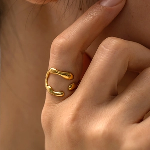 Close-up of elegant gold irregular streamline open ring worn on a woman's index finger
