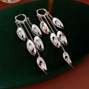 Détail de boucles d'oreilles à pompons argentés avec zircons sur un support en velours