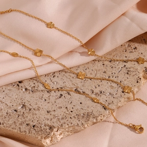 Detail of 18K gold-plated chain with flower pendants on pink satin and stone