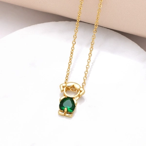 Detail of a gold-plated necklace featuring a little person pendant with a green heart zircon