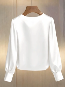 Detail of white satin long-sleeve blouse with round neck on a wooden hanger