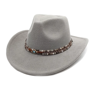 Detail of grey felt cowboy hat featuring silver studs and a blue evil eye charm detail