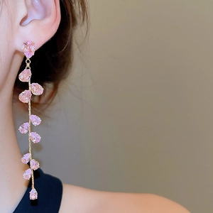 Close-up of pink teardrop crystal tassel earrings on model with golden metal finish