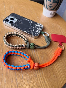 Detail of adjustable woven phone wrist lanyards in army green and orange patterns