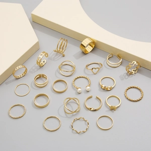 Detailed view of a 21-piece set of golden metal rings featuring heart and geometric designs