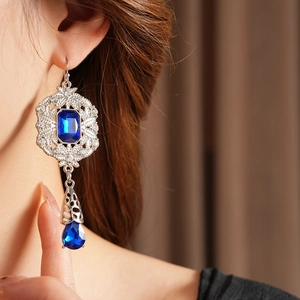 Macro shot of vintage silver earrings featuring blue rectangle and teardrop gems with crystals