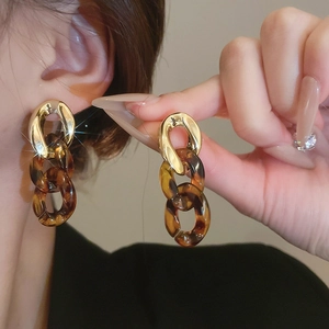 Detail of leopard print interlocking chain earrings in gold and tortoise resin finish