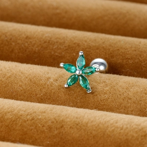 Macro view of flower stud earring with green marquise stones on brown velvet