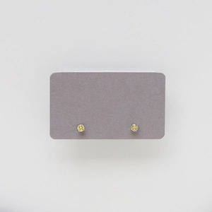 Close-up of yellow birthstone stud earrings in silver four-claw setting