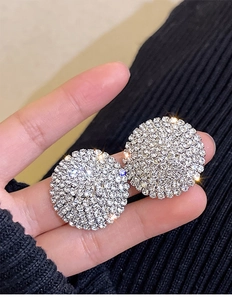 Macro shot of silver round stud earrings with sparkling pavé crystals and star effect