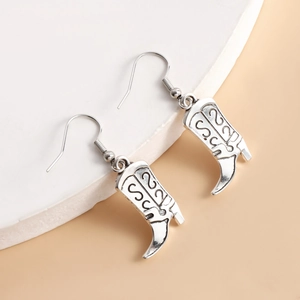 Détail de boucles d'oreilles bottes de cowboy en argent avec motifs gravés et crochets simples