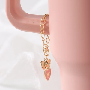 Detail of a pink enamel heart charm and gold butterfly pendant on a stylish cup chain