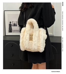 Detail of plush tote bag in beige faux fur with removable strap and gold hardware accents