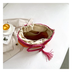 Top view of woven gradient pink straw tote with drawstring lining and tassel detail