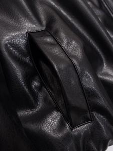 Macro shot of faux leather texture and side pocket design on a black bomber jacket