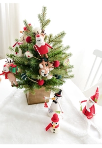 Miniature Christmas tree with wool felt reindeer and Santa ornaments on snowy base
