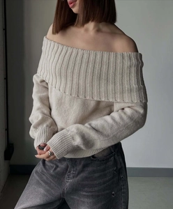 Detail view of beige off-shoulder knit sweater with thick chunky texture and foldover neckline