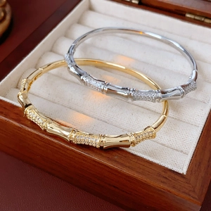 Detailed view of gold and silver bamboo-shaped zircon bracelets in a wooden jewelry box