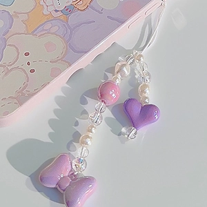 Close-up of beaded phone charm with purple hearts and bowknots on a wrist strap